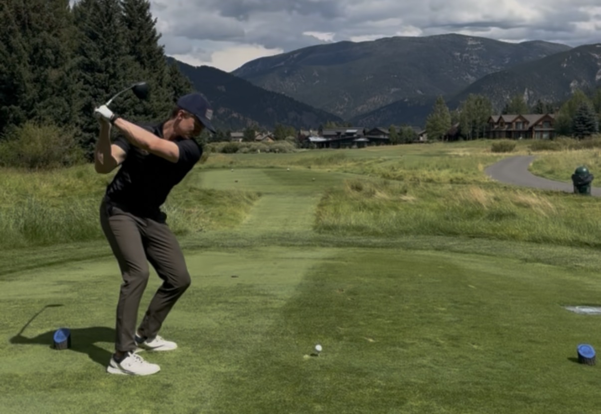 Golfer taking a swing on a scenic mountain course